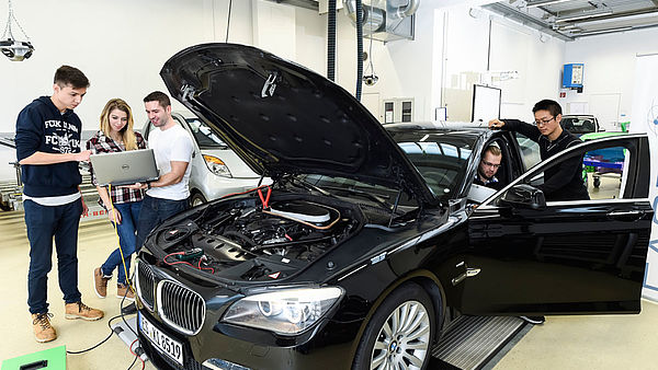 Fnf Studenten analysieren einen schwarzen 7er BMW.